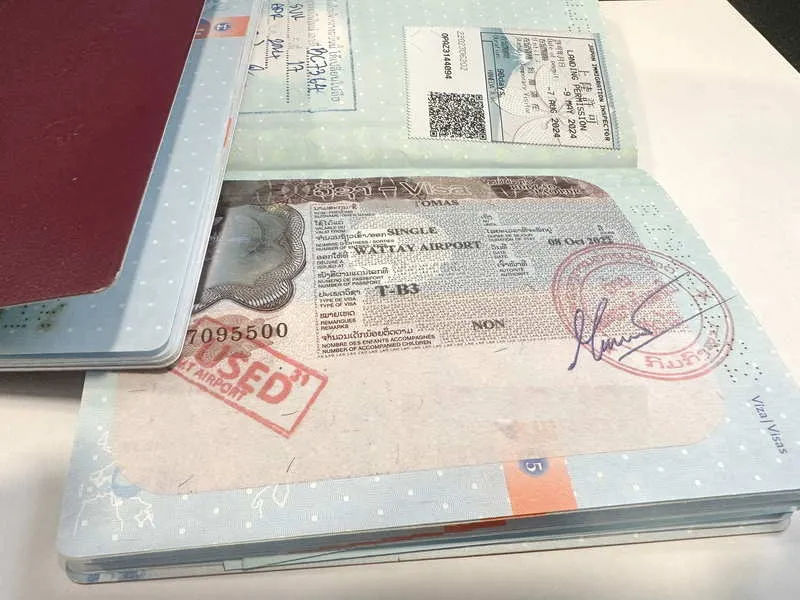 Open passport showing a Thai visa with stamps and a boarding pass tucked inside.
