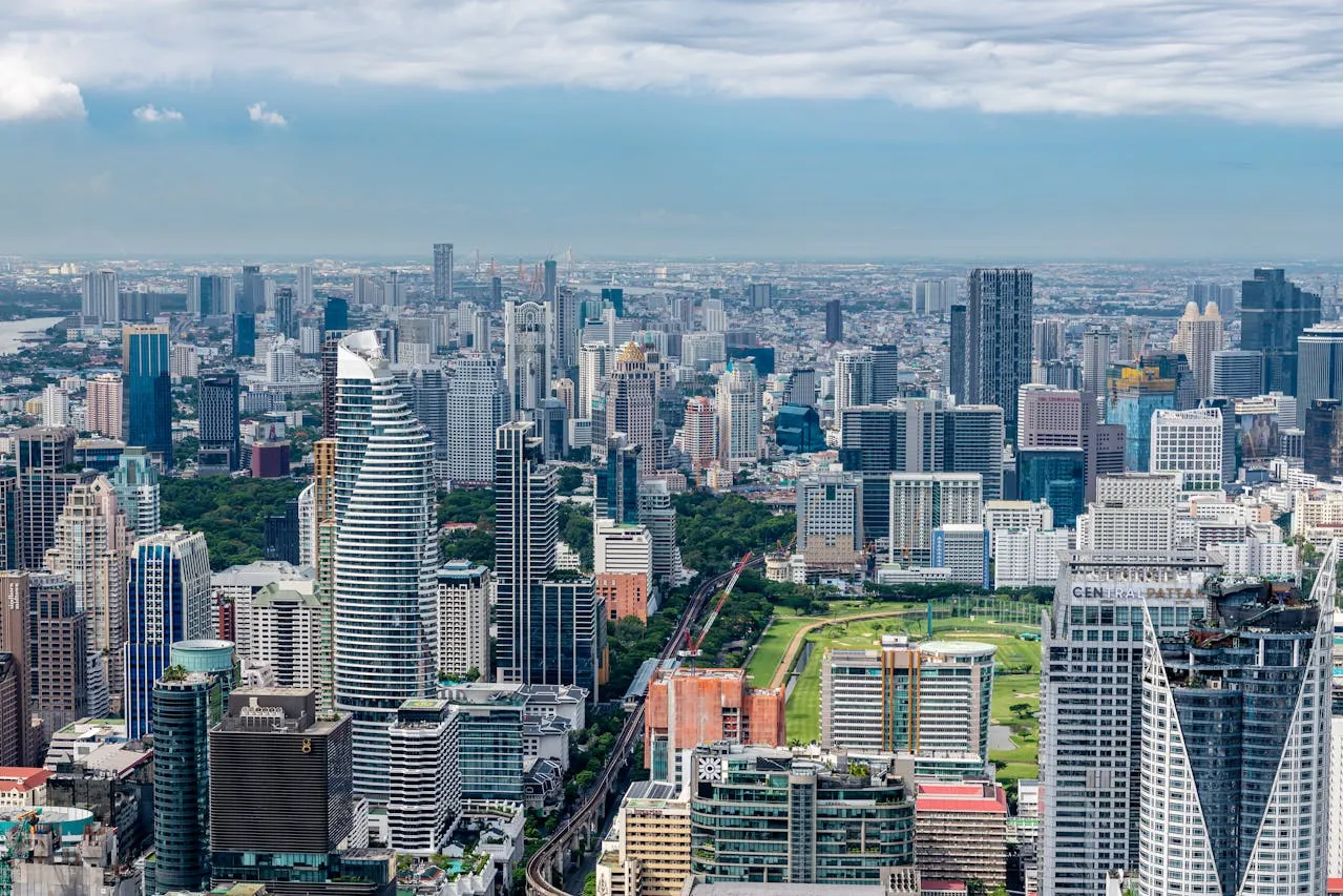 ภาพถ่ายทางอากาศของทิวทัศน์เมืองสมัยใหม่ที่มีตึกสูง สวนสาธารณะสีเขียว และท้องฟ้าปกคลุ