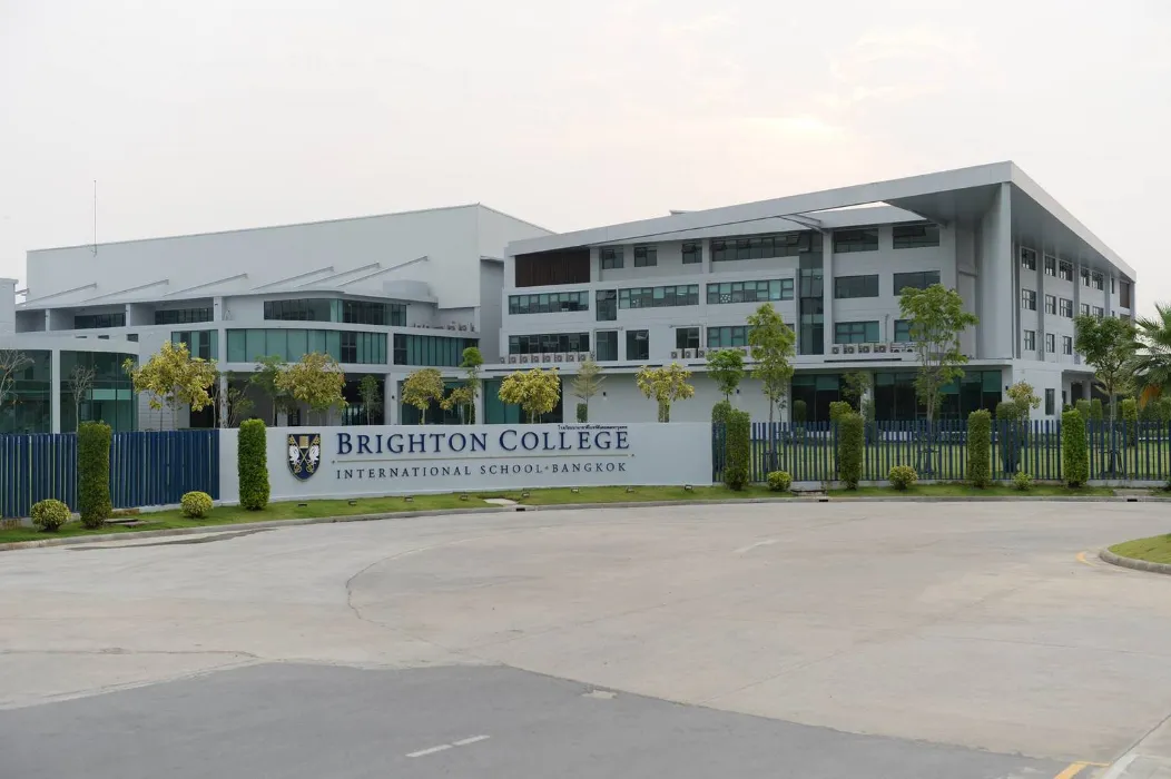 อาคารเรียนที่ทันสมัย ​​มีหน้าต่างบานใหญ่ และป้ายเขียนว่า "โรงเรียนนานาชาติไบรตันคอลเ