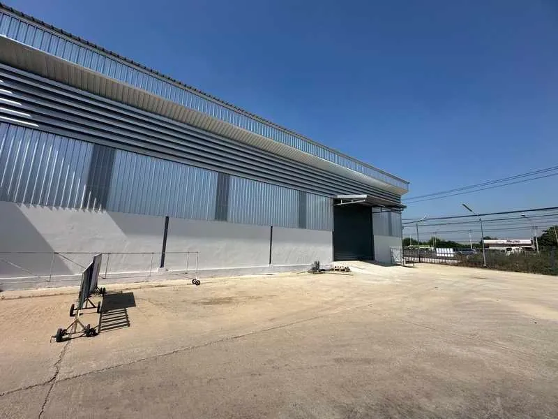 仓库外墙采用波纹金属板，装卸平台位于晴朗的蓝天下。