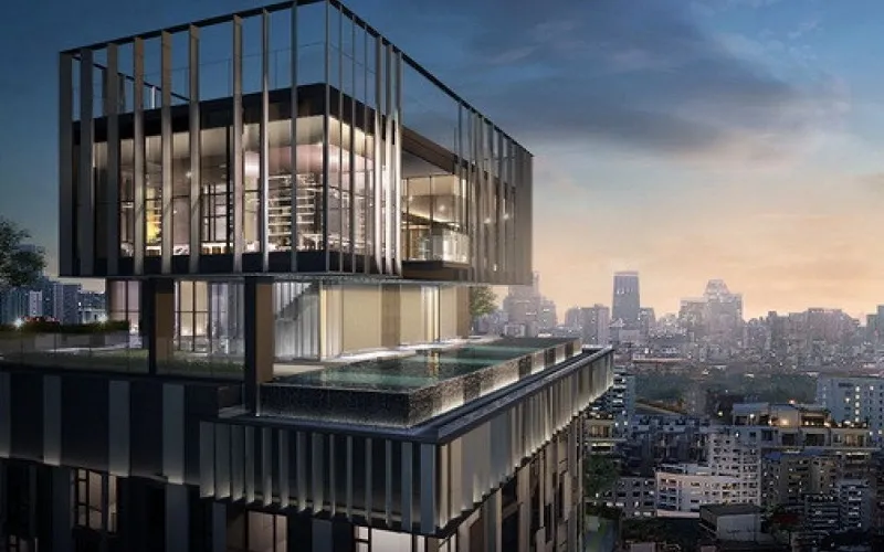 Modern building with glass facade and rooftop pool overlooking a city skyline at dusk.