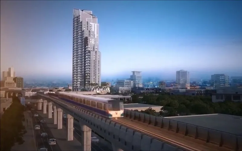 รถไฟที่กำลังเคลื่อนที่บนรางยกระดับแล่นผ่านตึกสูงในทิวทัศน์เมืองภายใต้ท้องฟ้าสีครามส