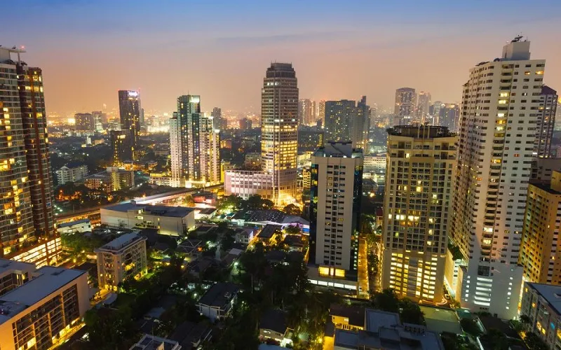 ภาพถ่ายทางอากาศของทิวทัศน์เมืองยามพลบค่ำ แสดงให้เห็นตึกระฟ้าสูงตระหง่านที่ส่องสว่าง 