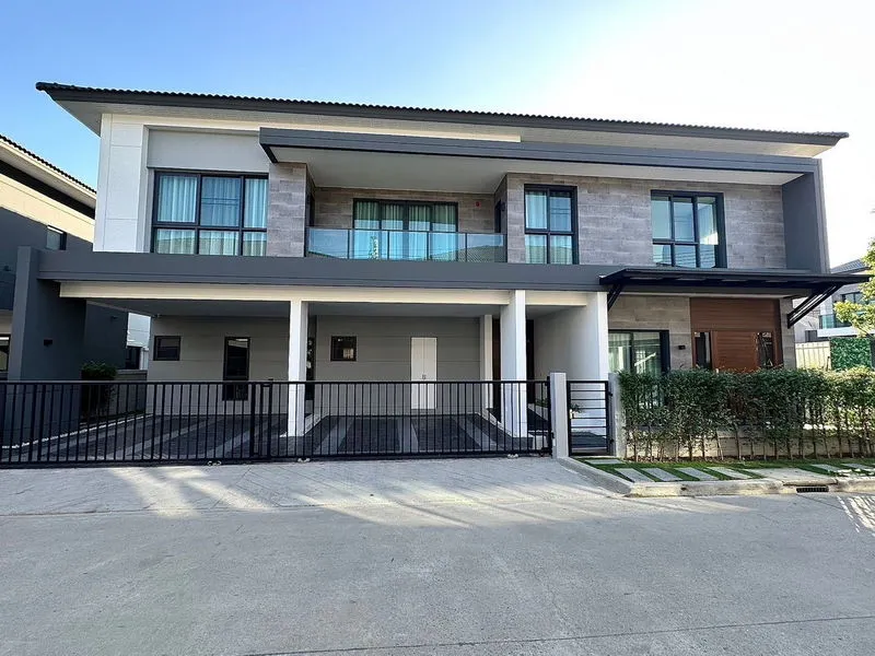 Modern two-story house with a minimalist facade, large windows, and a gated driveway.