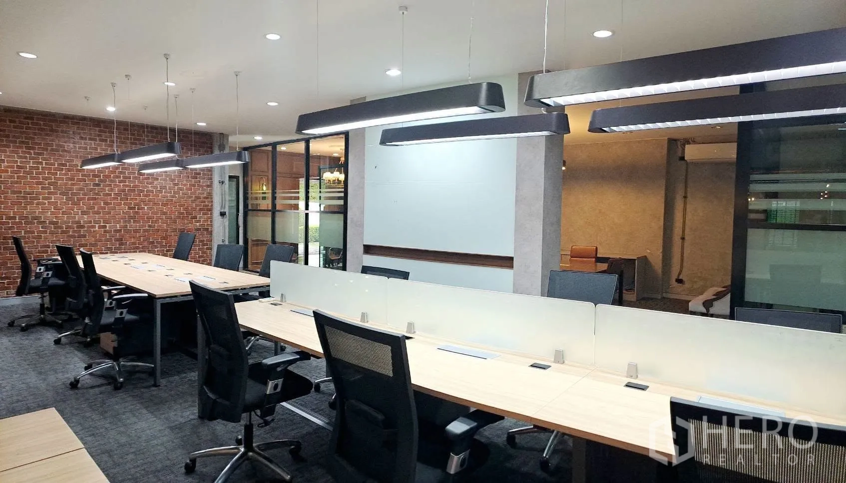Home Office for rent in Lat Phrao, Bangkok - Open office with pendant lights above shared desks and glass partitions.