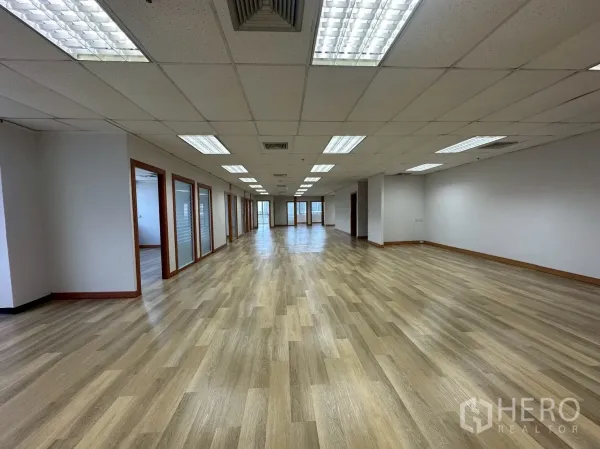 Office Space for rent - Open-plan office floor with rows of private glass-partitioned rooms and bright ceiling lights.