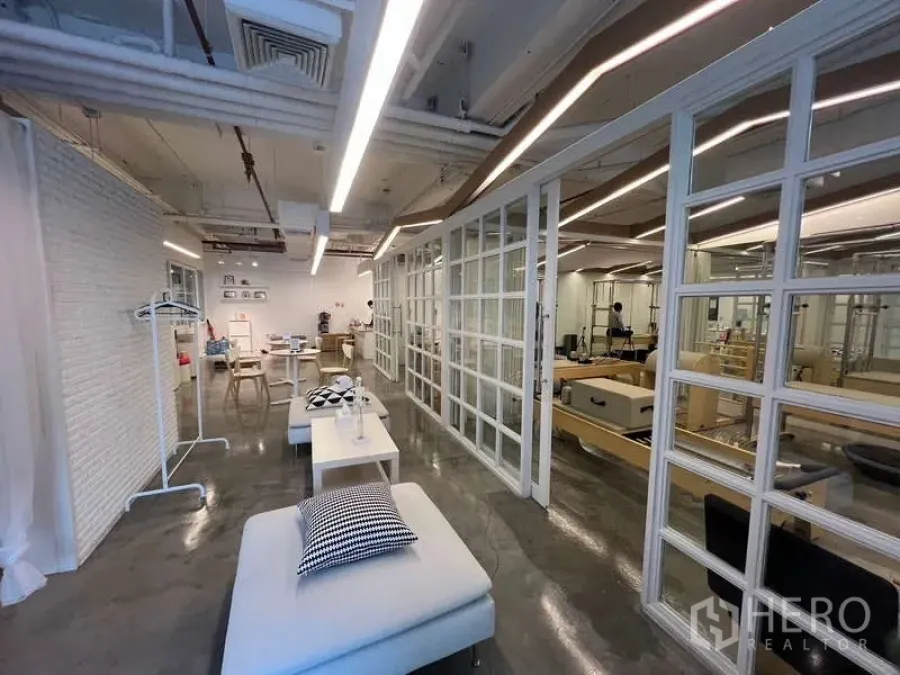 Retail Space for rent - Spacious retail area with grid glass partitions, daybed seating, and a polished concrete floor.