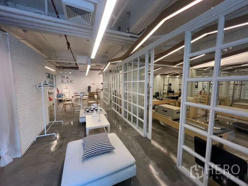 Retail Space for rent - Spacious retail area with grid glass partitions, daybed seating, and a polished concrete floor.