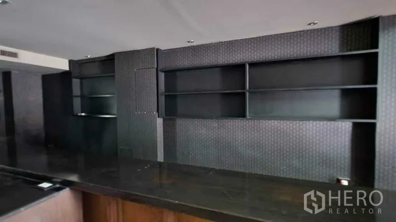 Shophouse for rent in Khlong Toei, Bangkok - Built-in black display shelves behind a counter zone in the commercial space.