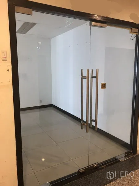 Office Space for rent in Watthana, Bangkok - Glass double-door entrance to a vacant office with tiled flooring.