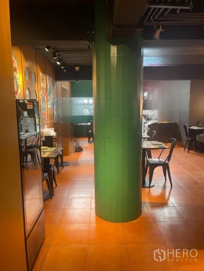 Shophouse for rent in Watthana, Bangkok - Hallway view of dining area with green tiled pillar and wall art.