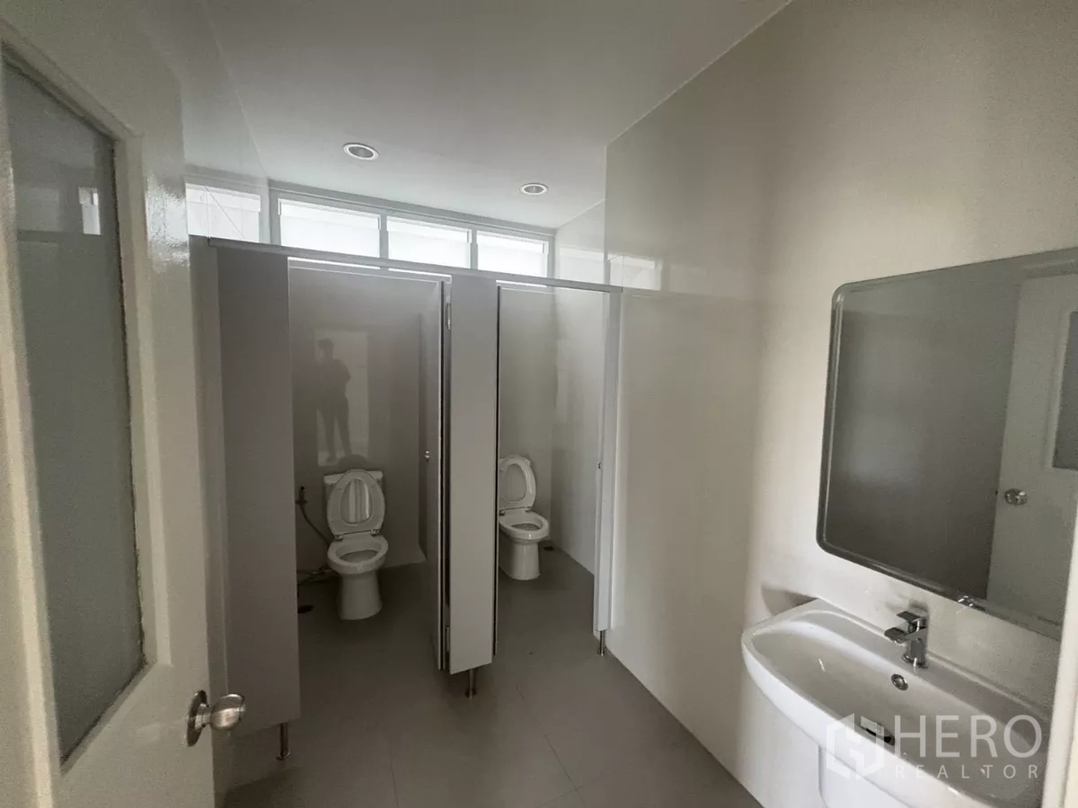 Factory for rent in Bang Phli, Samut Prakan - Restroom with multiple toilet stalls and basin with mirror.