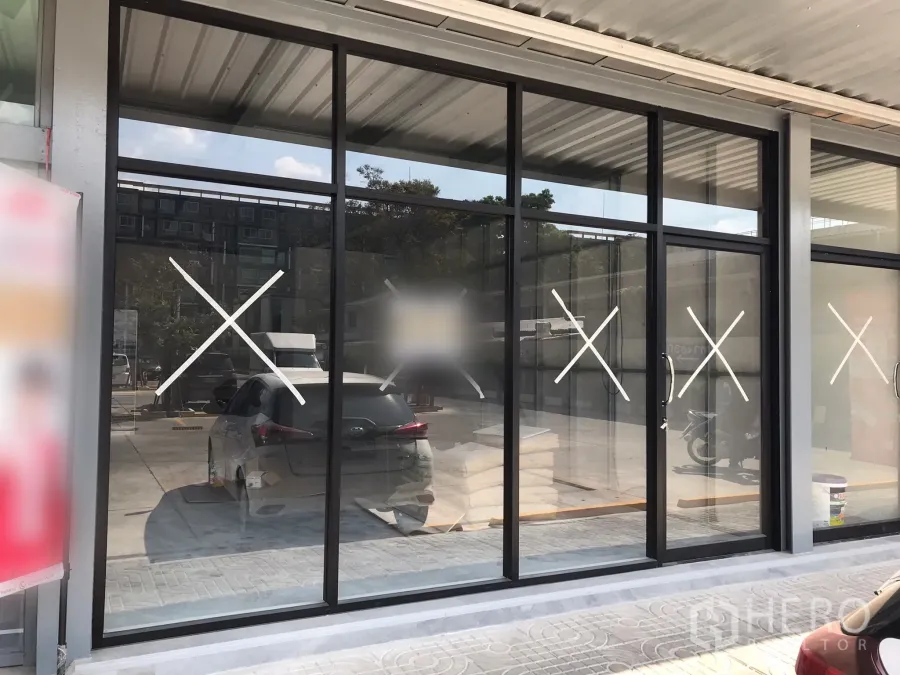 Retail Space for rent in Khlong Toei, Bangkok - Street-facing retail unit with floor-to-ceiling glass storefront, black aluminum frames, covered walkway, and parking out front.