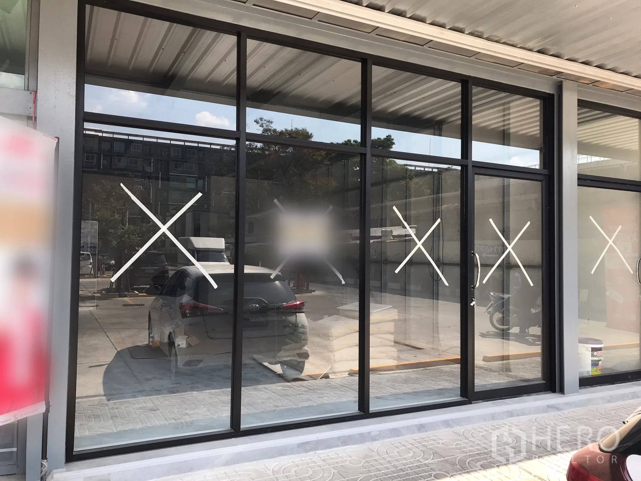 Retail Space for rent in Khlong Toei, Bangkok - Street-facing retail unit with floor-to-ceiling glass storefront, black aluminum frames, covered walkway, and parking out front.
