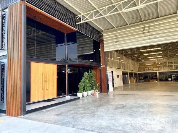 货栈 出售在Min Buri, Bangkok - 仓库外立面，玻璃办公室与木质装饰，配大型卷闸入口。
