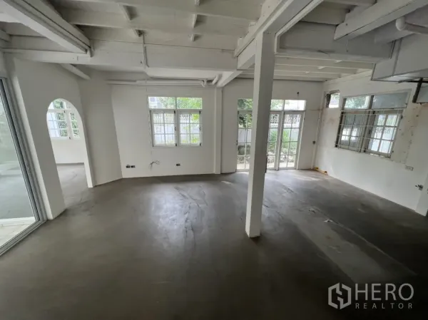 Detached House for rent or sale in Sathon, Bangkok - Open-plan living area with support columns, arched doorway and French doors to patio.