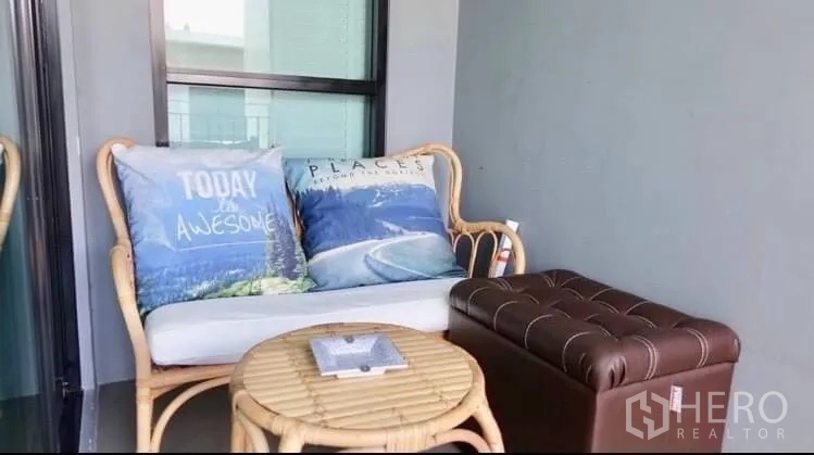 Townhouse for rent or sale in Suan Luang, Bangkok - Compact balcony with rattan loveseat, ottoman and a small round table.
