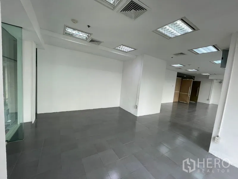 Office Space for rent - Clean white-walled section of the office with corner glazing and ducted air vents.