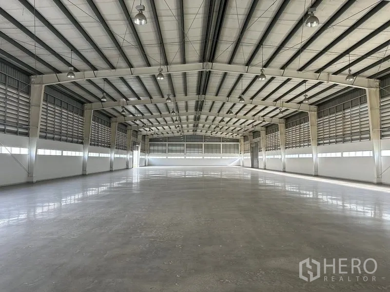 Factory for rent in Phra Nakhon Si Ayutthaya - Empty warehouse highlighting wide column-free space, louvered side walls, and bright lighting.