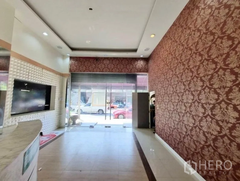 Shophouse for rent in Watthana, Bangkok - Lobby view toward the street through a glass storefront and roller shutter.