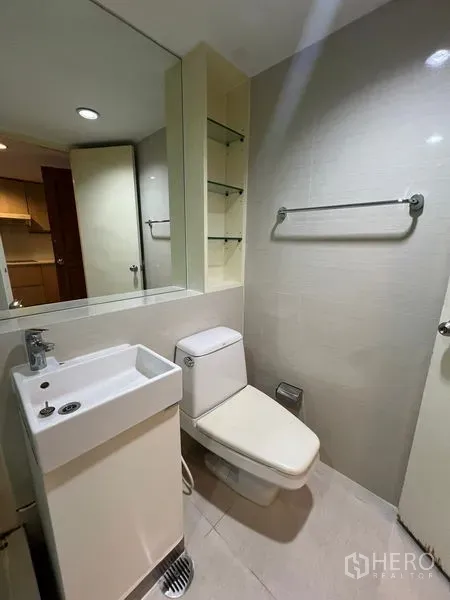 Condominium for rent or sale in Khlong Toei, Bangkok - Compact guest bathroom with sink, toilet and open shelving.