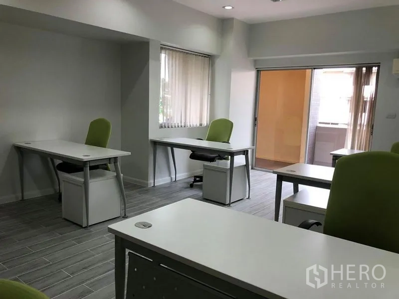 办公空间 出租在Khlong Toei, Bangkok - 办公室转角，窗户与推拉门通向小阳台，书桌配可上锁抽屉柜。