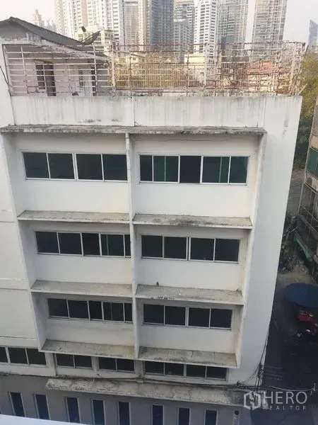 办公空间 出租在Khlong Toei, Bangkok - 澎蓬区域带成排窗户的中层办公楼，可见城市天际线。