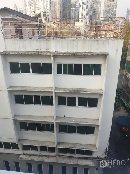 办公空间 出租在Khlong Toei, Bangkok - 澎蓬区域带成排窗户的中层办公楼，可见城市天际线。