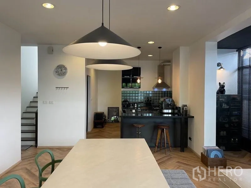 Detached House for sale in Sai Mai, Bangkok - Open-plan dining and kitchen area with pendant lights and herringbone wood flooring.