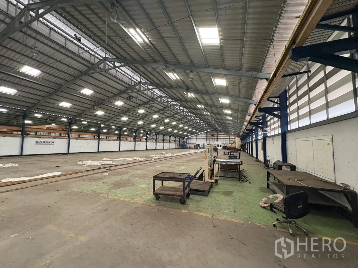 Factory for rent in Phra Pradaeng, Samut Prakan - Long‑span roof hall with lighting and worktables along one side.