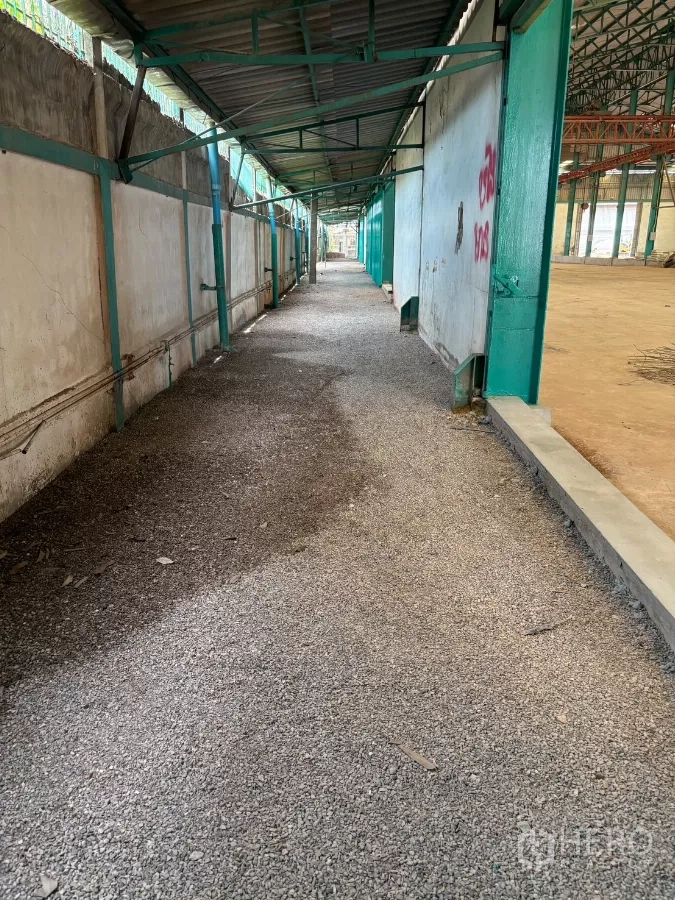 Factory for rent in Mueang Samut Sakhon, Samut Sakhon - Covered side walkway with corrugated roof and gravel path alongside the factory wall.