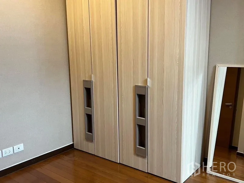 Condominium for rent - Bedroom corner showing light wood double wardrobe and a freestanding mirror.