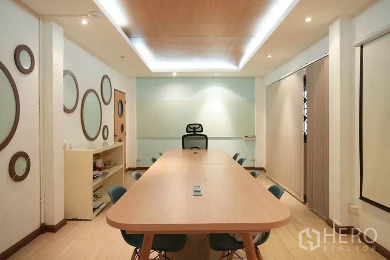 Home Office for rent in Wang Thonglang, Bangkok - Modern meeting room with long conference table, recessed lighting and a glass whiteboard.