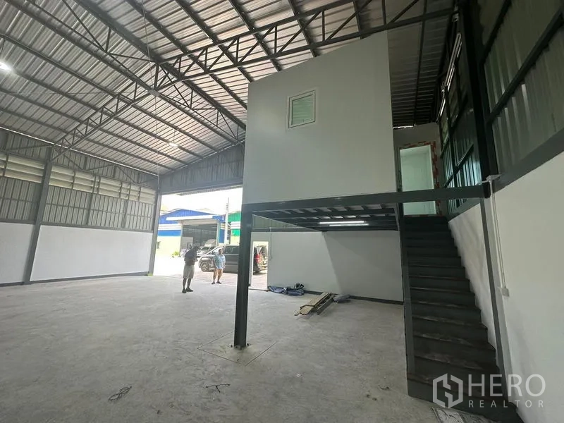 Warehouse for rent in Khlong Toei, Bangkok - Steel staircase to mezzanine office next to large warehouse entry; spacious floor area.