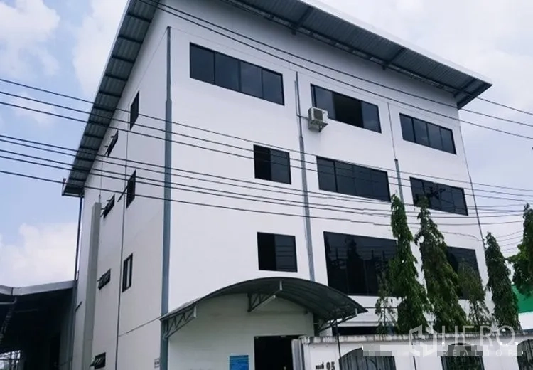 Warehouse for rent in Suan Luang, Bangkok - Exterior of a modern multi-storey industrial building with canopy and large windows.