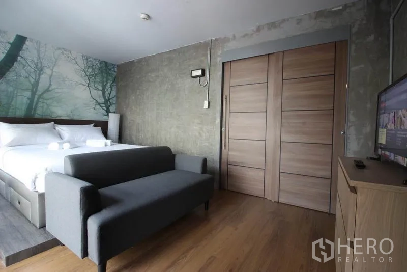 Office Space for rent or sale in Bang Rak, Bangkok - Suite view with gray sofa, wooden sliding doors, and a TV cabinet.