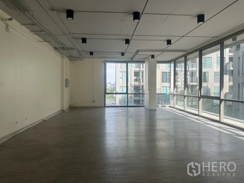 Office Space for rent in Phra Khanong, Bangkok - Bright open-plan office with floor-to-ceiling windows, city views, wood-look floors, and exposed ceiling lights.