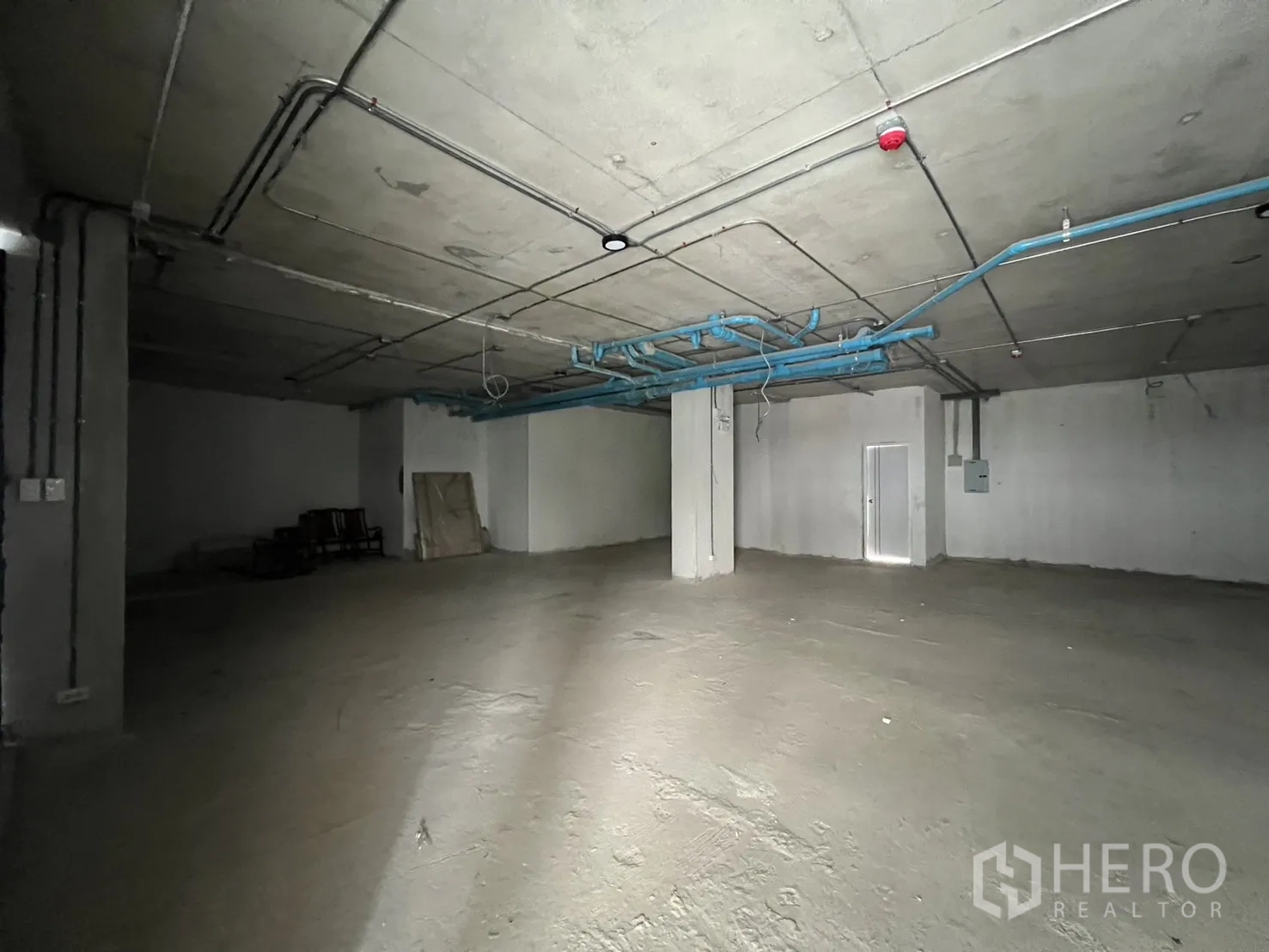 Retail Space for rent - Large shell-and-core retail interior with high ceiling, concrete floor and exposed services.
