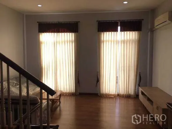 Home Office for rent in Wang Thonglang, Bangkok - Upstairs lounge with wood floors, tall curtained windows, air-conditioning and stair rail in a Bangkok home office.