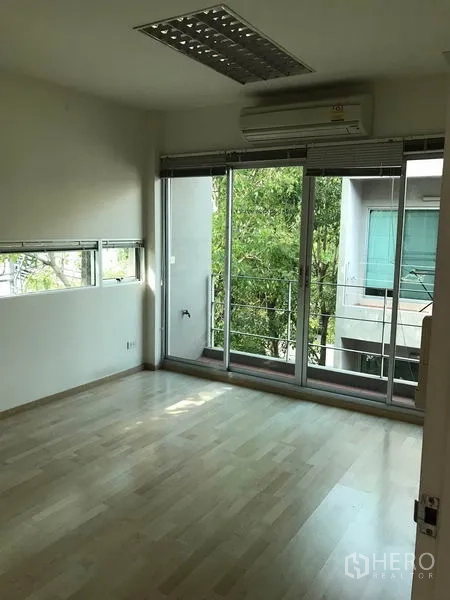 Townhouse for rent in Suan Luang, Bangkok - Upper floor bedroom with air-conditioning and sliding doors to a balcony.
