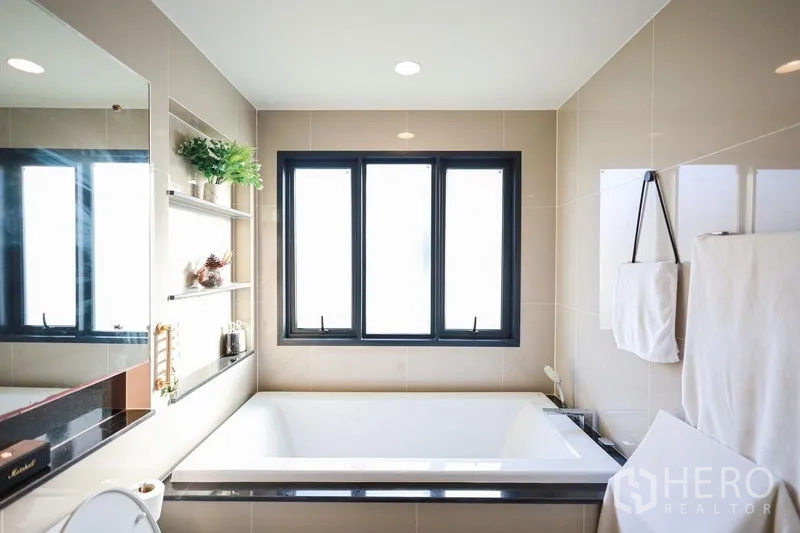 Detached House for rent or sale in Lam Luk Ka, Pathum Thani - Bathroom with large soaking tub and wide window providing natural light.