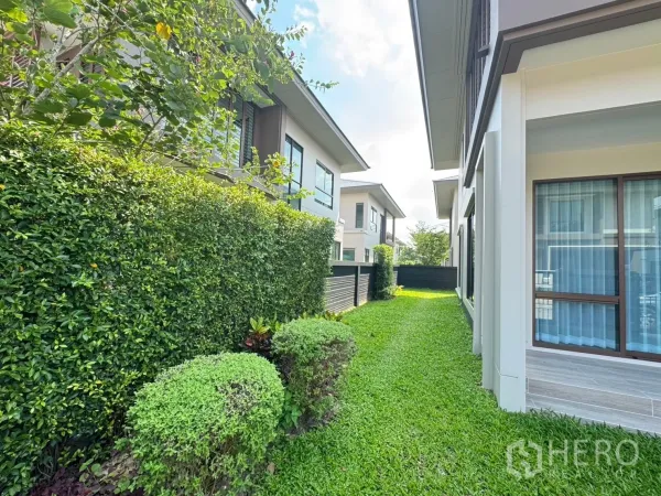 Detached House for rent or sale in Bang Kapi, Bangkok - Side garden with trimmed hedges and green lawn between neighboring houses.