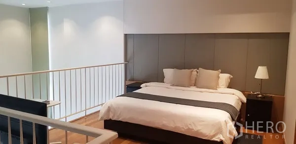 Condominium for rent in Khlong Toei, Bangkok - Mezzanine bedroom with king bed, side tables and railing overlooking living room.