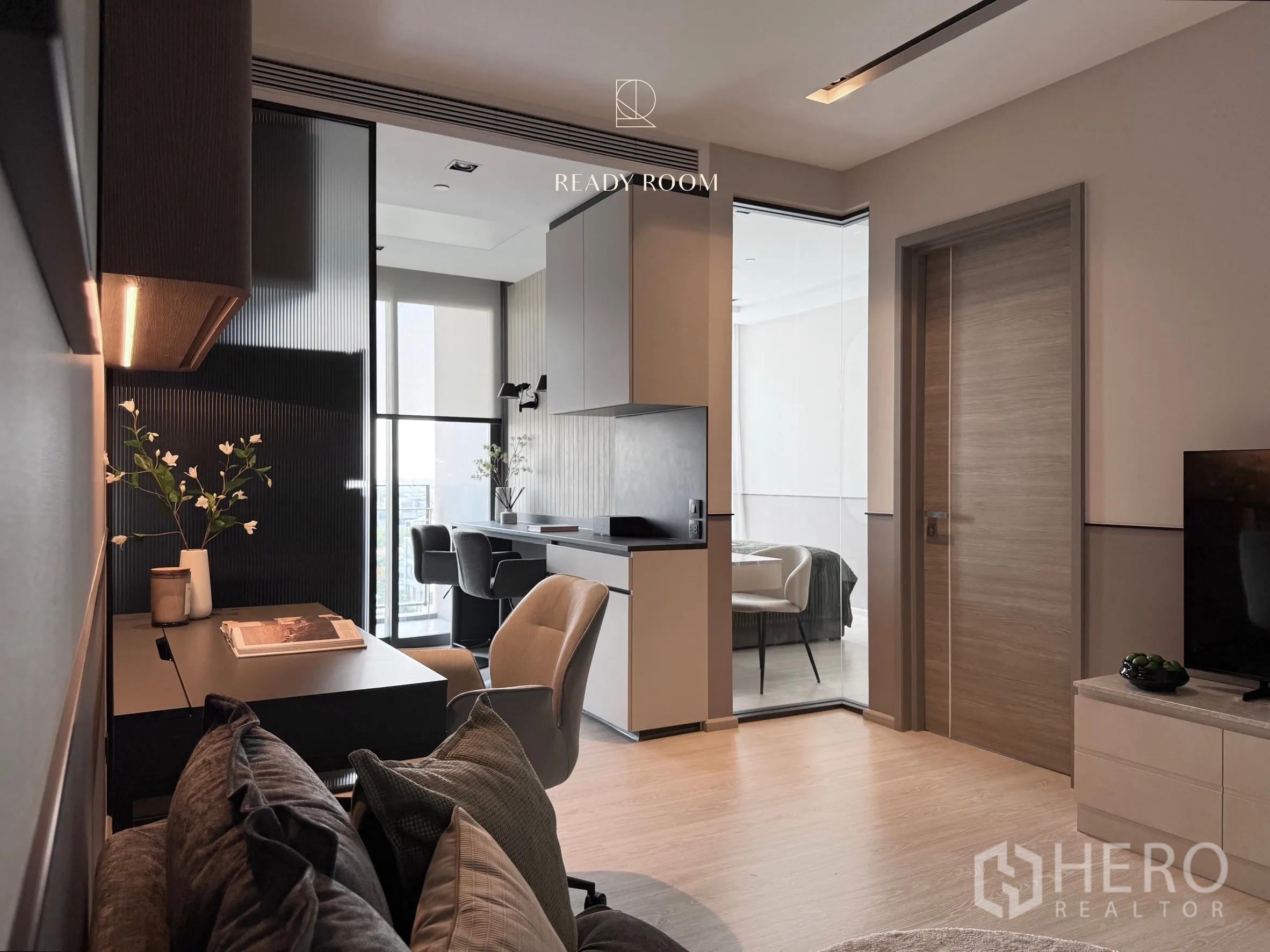 Condominium for rent in Khlong Toei, Bangkok - Work desk and kitchen leading toward a bright bedroom with a glass partition.