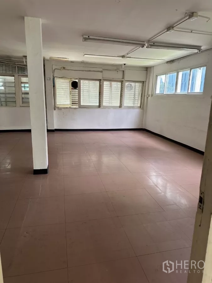Shophouse for sale in Watthana, Bangkok - Bright upper-floor open room with multiple windows and tiled floor.