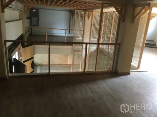 Retail Space for rent in Khlong Toei, Bangkok - Mezzanine level with wood floors and glass railing overlooking the retail area, suitable for lounge or showcase.