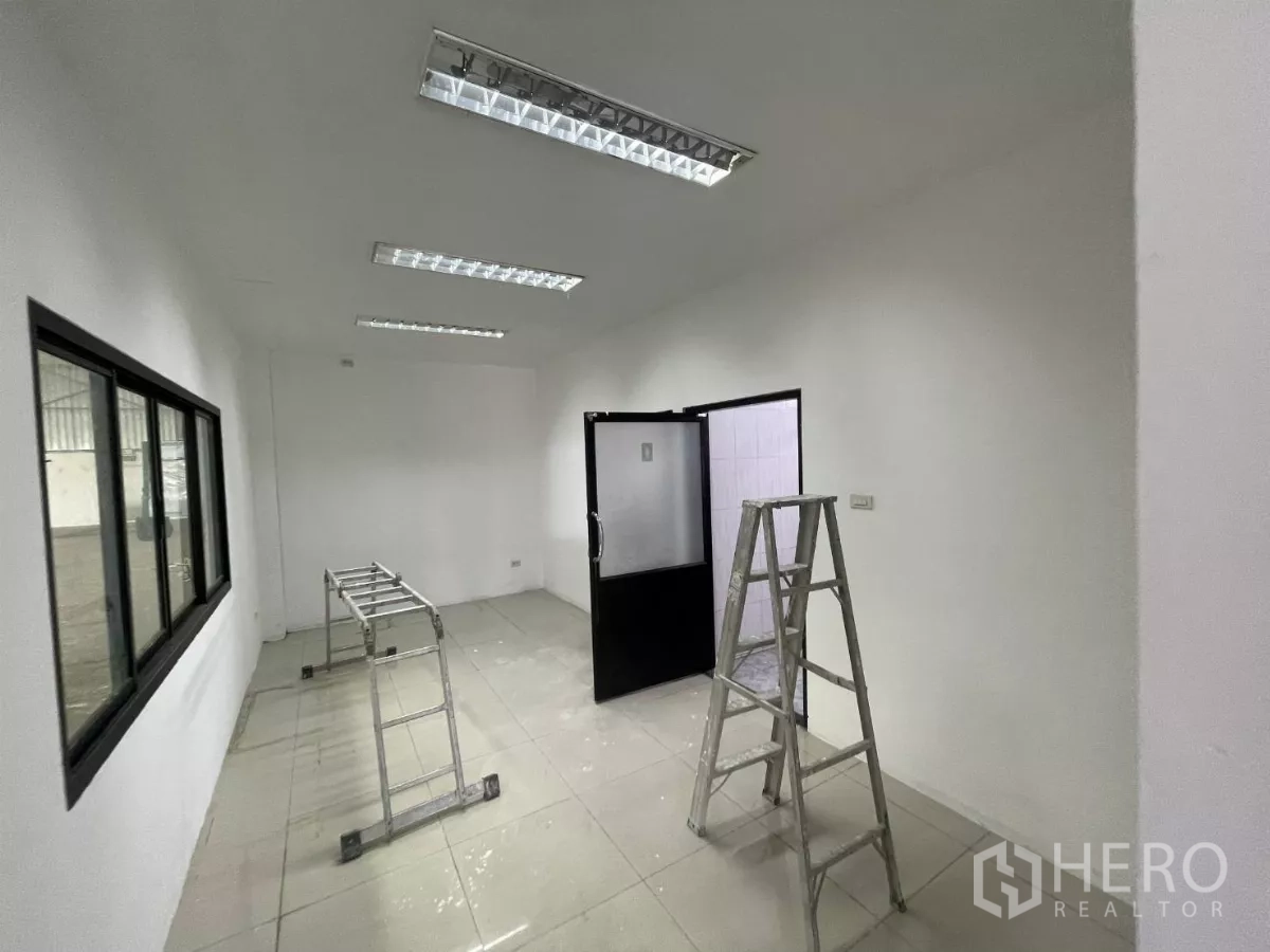 Warehouse for rent in Lat Krabang, Bangkok - Bright office room with tiled floor, fluorescent lights, and black-framed windows.