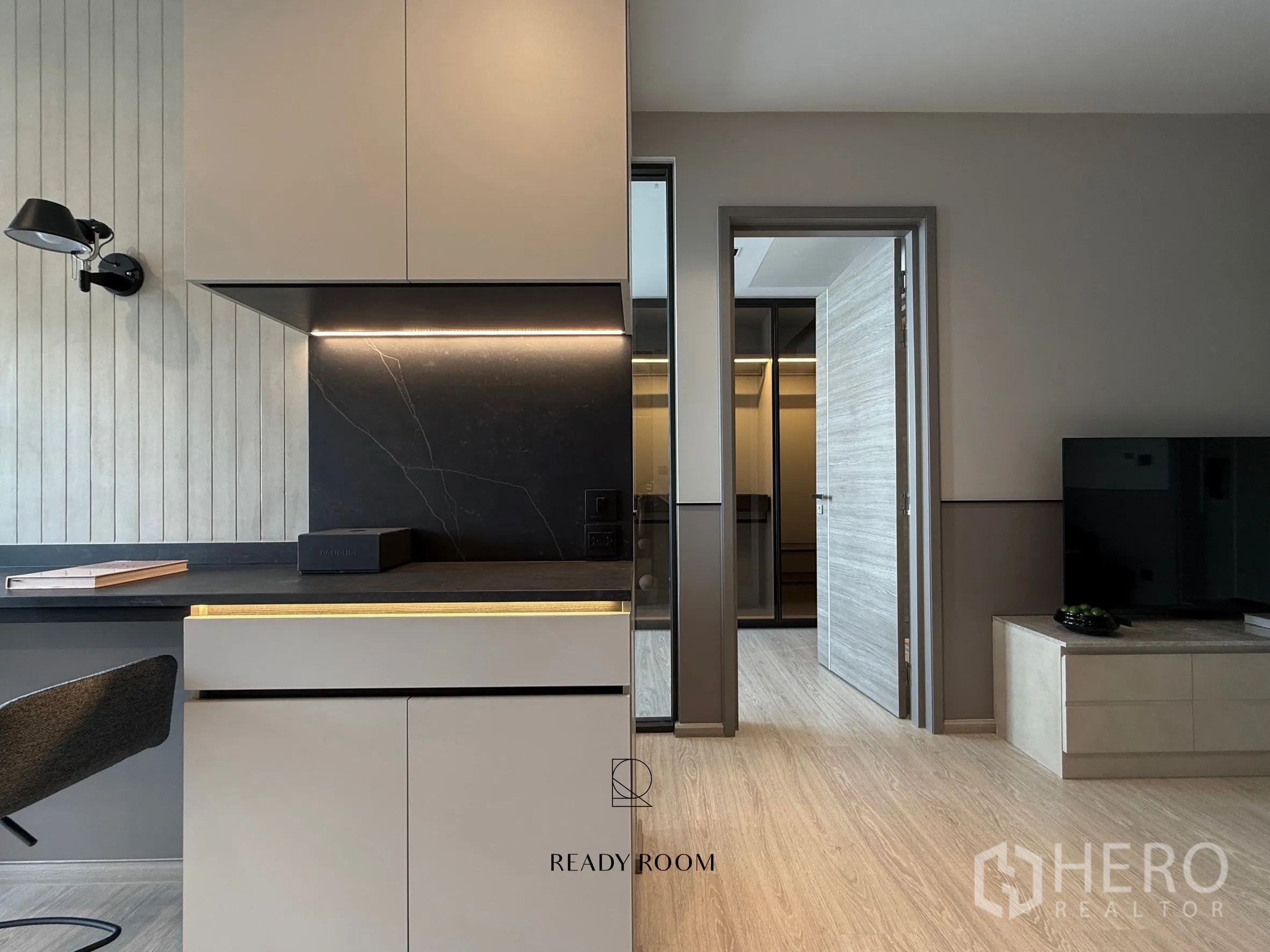 Condominium for rent in Khlong Toei, Bangkok - Close-up of minimalist kitchen with dark backsplash and hallway to wardrobe.