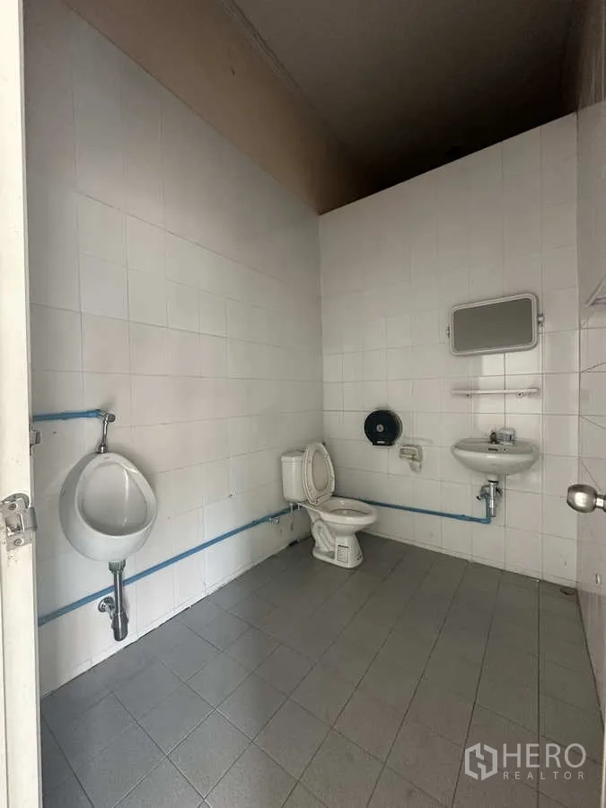 Warehouse for rent in Phra Nakhon Si Ayutthaya - Clean tiled restroom with toilet, urinal and sink inside the warehouse facility.