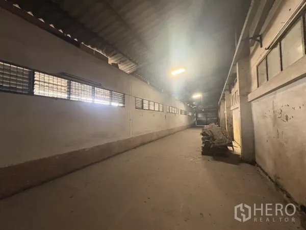 Warehouse for rent in Khlong Toei, Bangkok - Long warehouse aisle with ventilated louver windows, concrete floor and overhead lighting.